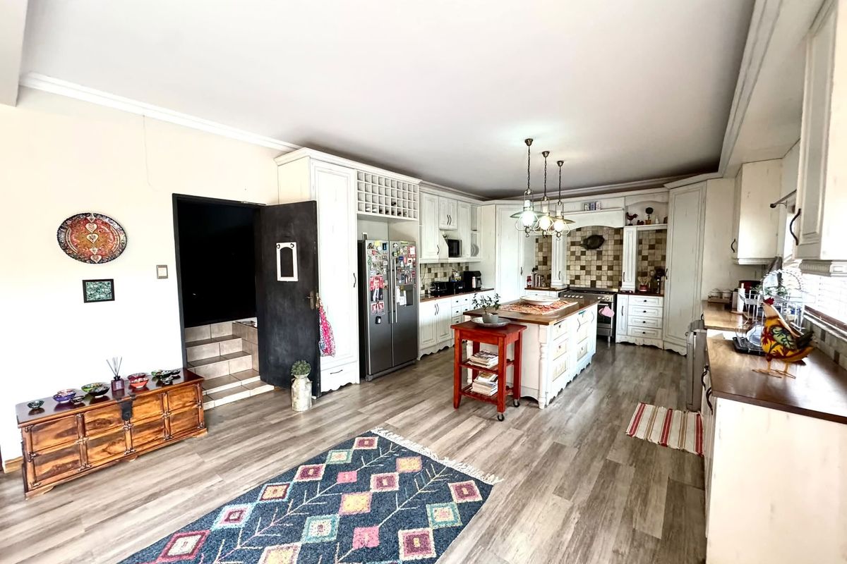 Spacious kitchen featuring white cabinetry, a central island, tiled backsplash, and wood-look laminate flooring, offering a functional and inviting culinary space.