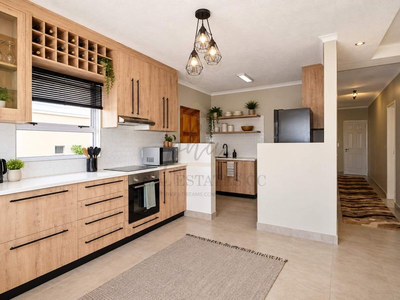 Modern kitchen featuring light wood cabinetry, stone countertops, integrated appliances, and a functional scullery area with additional storage and sink.