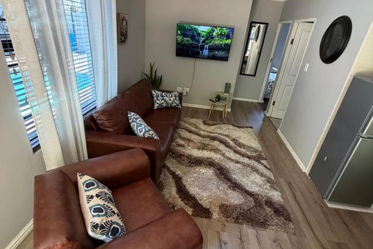 A cozy living room featuring wood-look laminate flooring, neutral wall tones, and a ceiling-mounted light fixture.