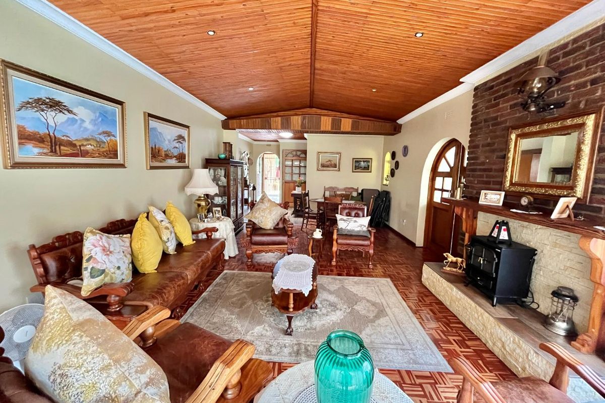 Spacious living room featuring a vaulted timber ceiling, exposed brick fireplace with a wood-burning stove, and traditional parquet flooring.