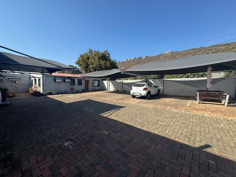 Spacious paved driveway area featuring multiple shade cloth carports and secure perimeter walling, providing ample off-street parking space.