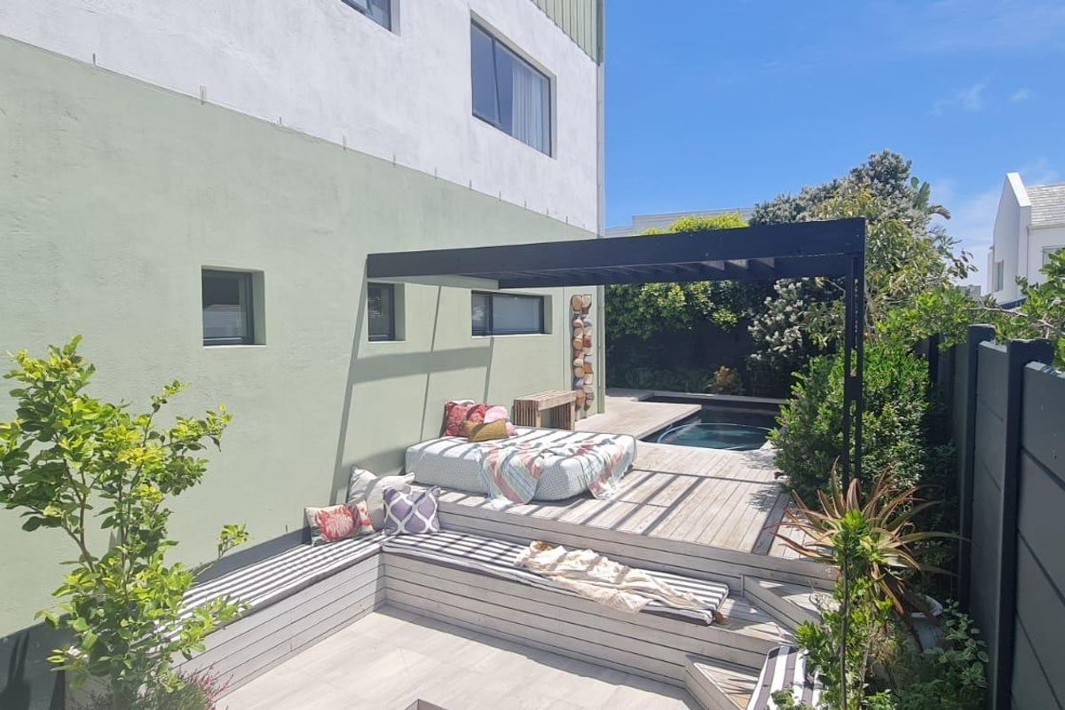 A private rear garden area featuring a raised timber deck, built-in seating, a pergola structure, and a small plunge pool.