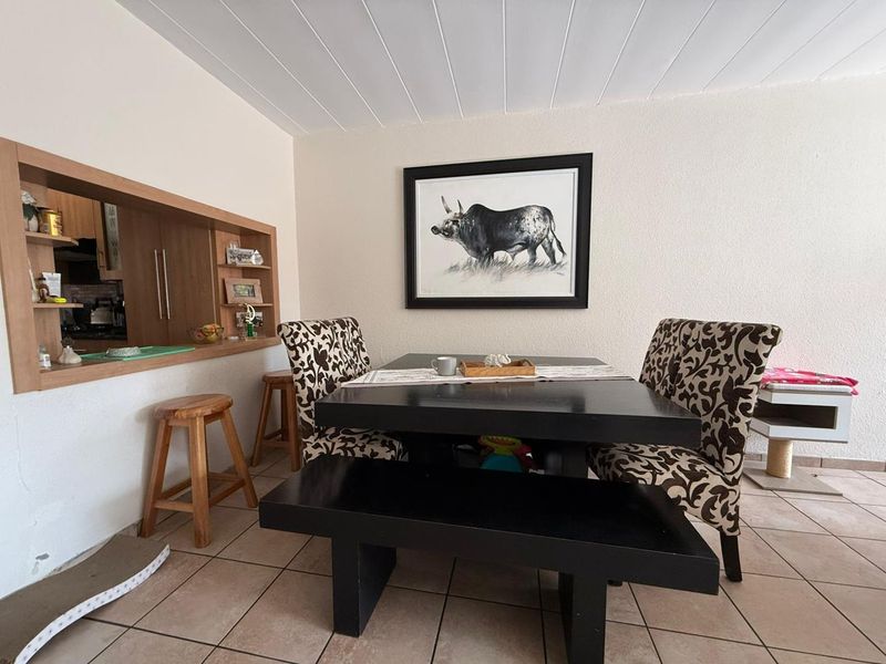 Dining area featuring tiled flooring, a tongue and groove ceiling, and a convenient serving hatch connecting to the kitchen.