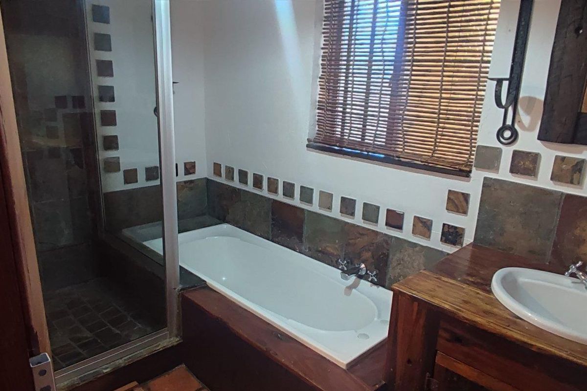Bathroom featuring a built-in bathtub, separate glass-enclosed shower, and a timber vanity with a basin.