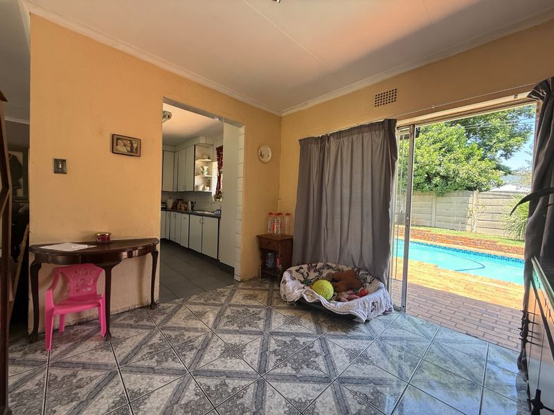 Open plan living area featuring tiled floors and a sliding door providing direct access to the outdoor pool area, with an adjacent kitchen space.