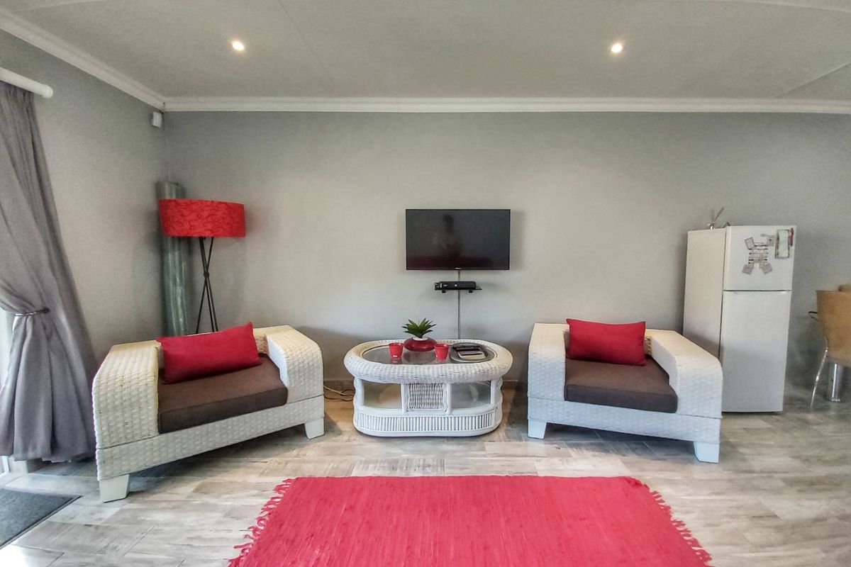 A living area featuring light-toned wood-look flooring, recessed ceiling lighting, and a wall-mounted television setup.