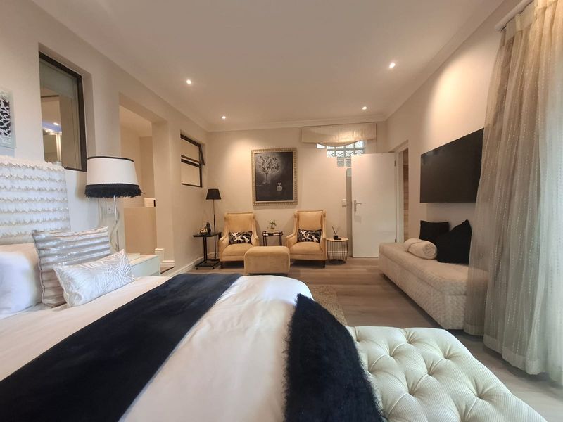 Spacious bedroom featuring modern recessed lighting, neutral laminate flooring, and a unique glass block accent window, creating a bright and comfortable living space.