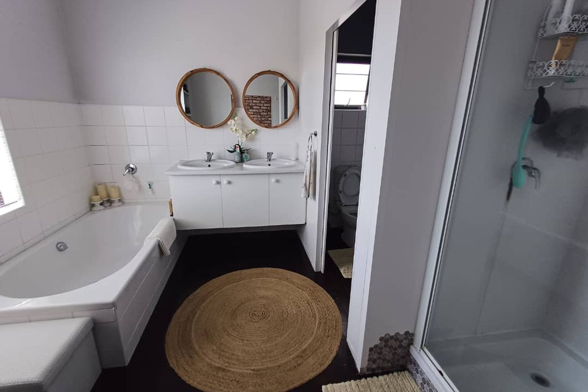 A functional bathroom featuring a built-in bathtub, a separate glass-enclosed shower, and a double vanity with integrated sinks.