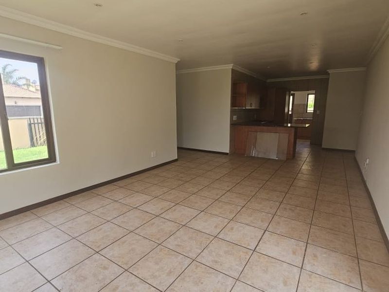 Spacious open-plan living and kitchen area featuring neutral tiled flooring, recessed lighting, and built-in cabinetry, offering a versatile layout for modern living.