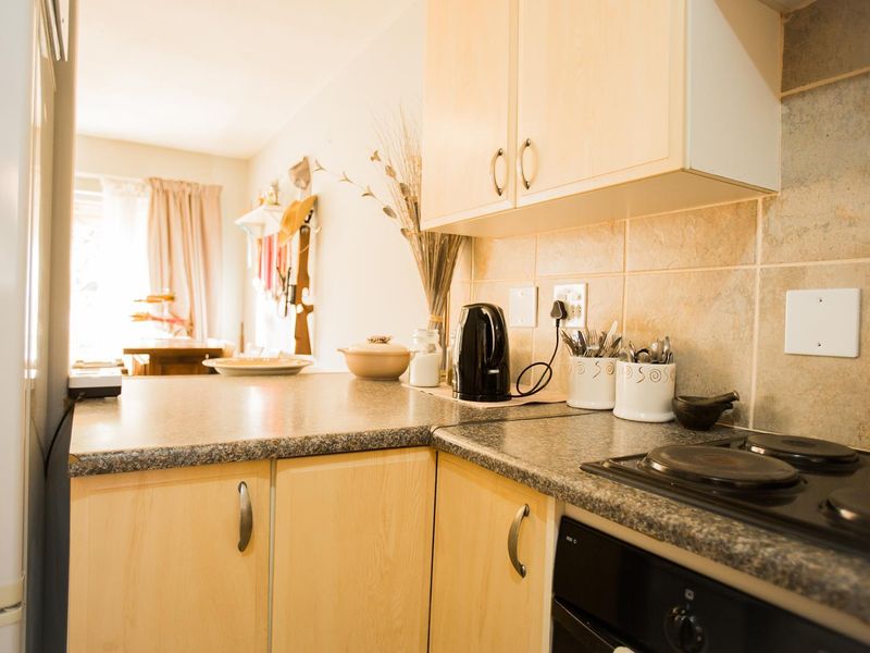 A functional kitchen featuring light wood-finish cabinetry, granite-look laminate countertops, and a tiled backsplash, with integrated electric cooking appliances.