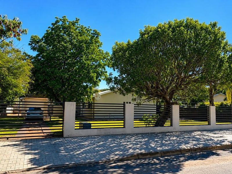 Front view of the property featuring a modern horizontal slat metal fence with concrete pillars and a paved sidewalk.
