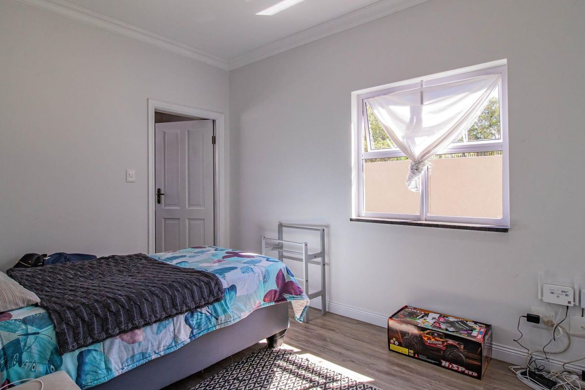 A bright bedroom featuring laminate flooring, neutral walls, and a window with a stone sill.
