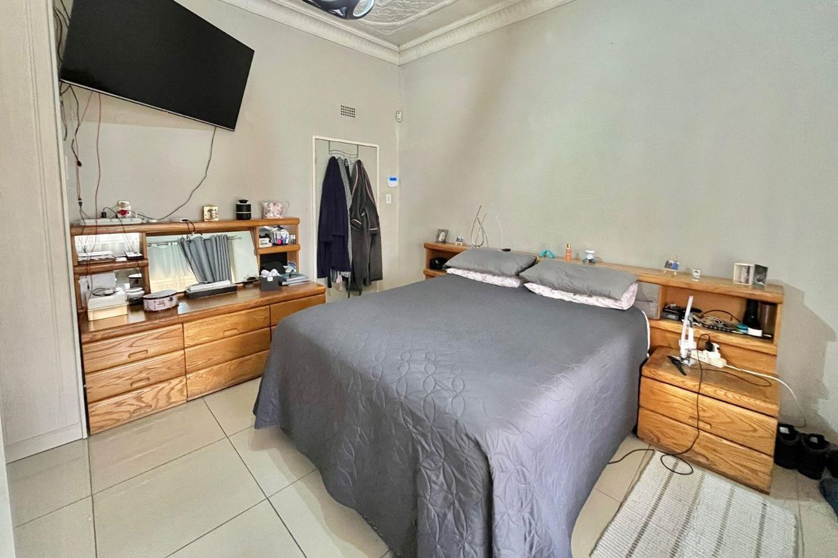 A bedroom featuring tiled flooring, decorative ceiling cornicing, and built-in wooden cabinetry.