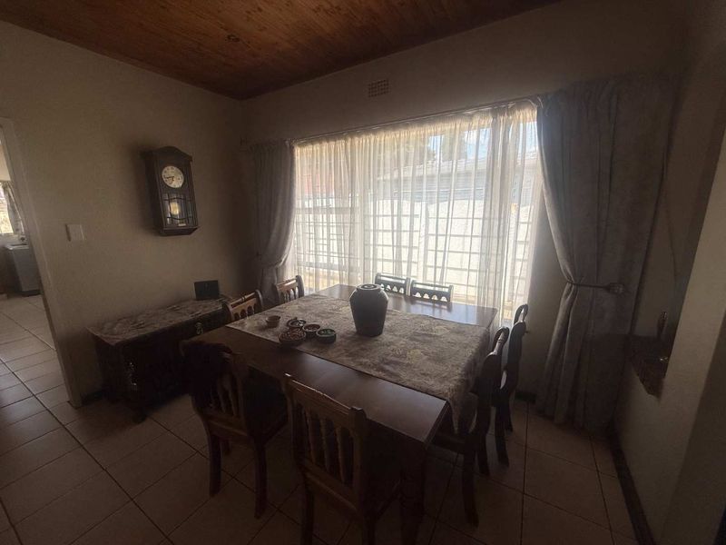 A dining room featuring tiled flooring and a timber ceiling, with a large window providing natural light.
