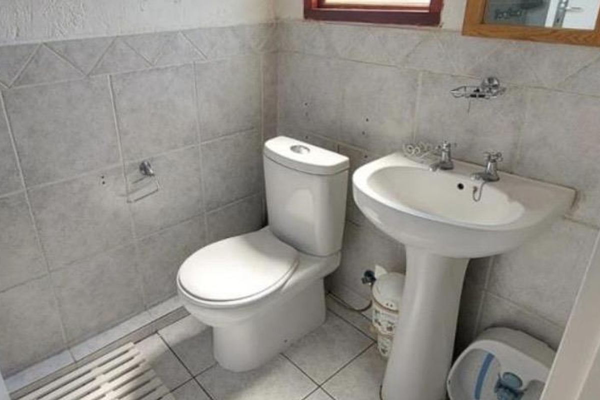 A functional bathroom featuring a pedestal basin and a standard toilet with neutral wall and floor tiling.