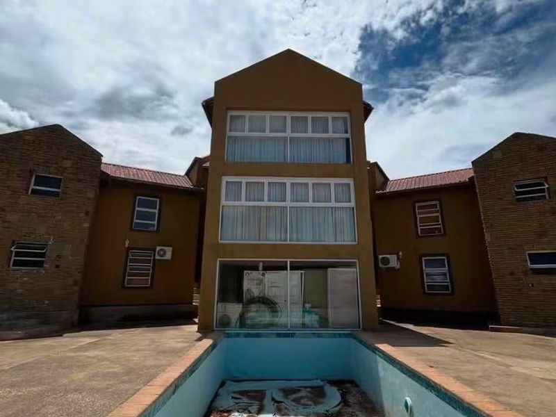 Exterior view of a multi-story residential building featuring a large, empty swimming pool in need of maintenance and repair.