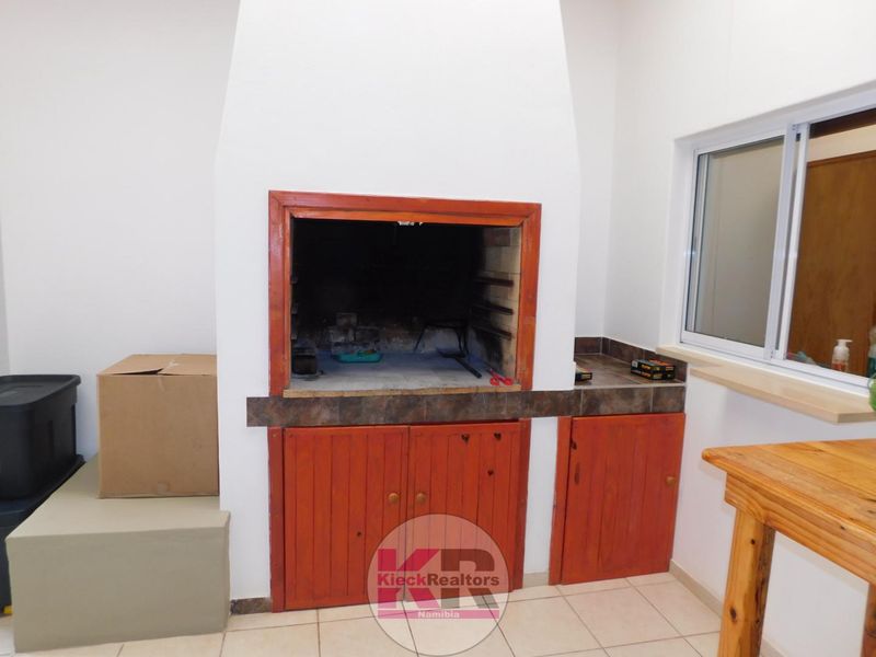 An indoor entertainment area featuring a built-in braai with integrated cabinetry and tiled flooring, providing a functional space for social gatherings.