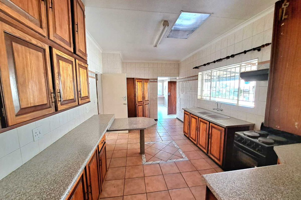 Spacious kitchen featuring wooden cabinetry, laminate countertops, a double basin sink, and a freestanding stove, offering a functional layout with ample storage space.
