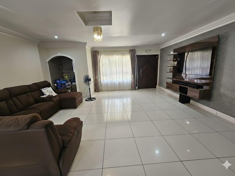 Spacious living room featuring large format porcelain floor tiles, a modern built-in media wall unit, and elegant recessed ceiling lighting.