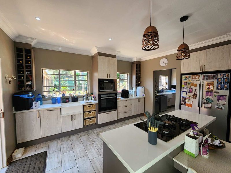 Modern kitchen featuring a central island with gas hob, farmhouse sink, built-in oven, microwave, and ample cabinetry with integrated wine storage.