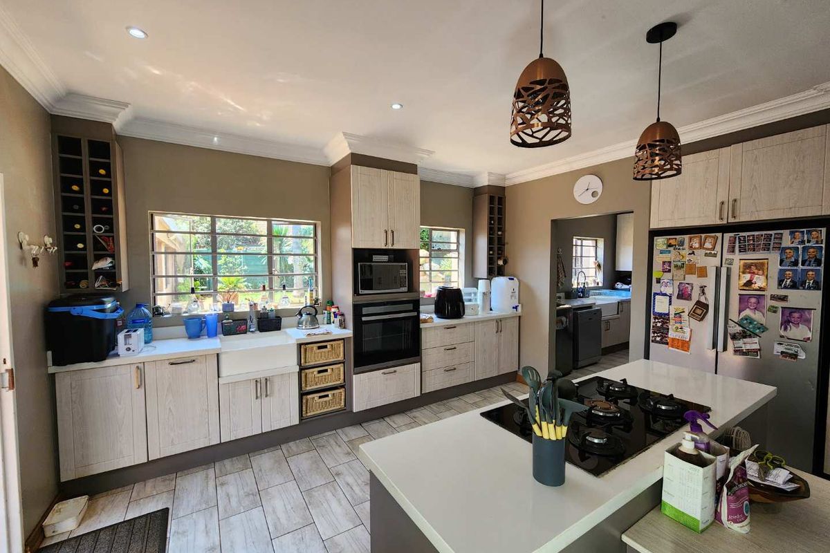 Modern kitchen featuring a central island with gas hob, farmhouse sink, built-in oven, microwave, and ample cabinetry with integrated wine storage.