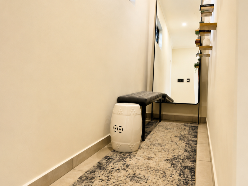 A well-maintained hallway featuring neutral tiled flooring, clean wall finishes, and a high-level window providing natural light.