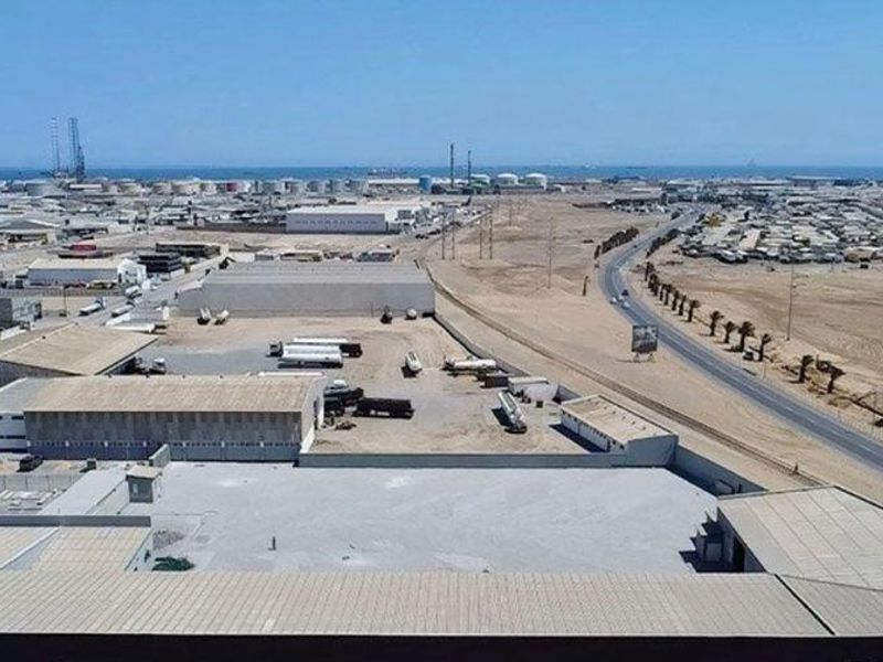 Aerial view of an industrial property featuring warehouse structures, a large paved yard, and surrounding access roads in an industrial zone.