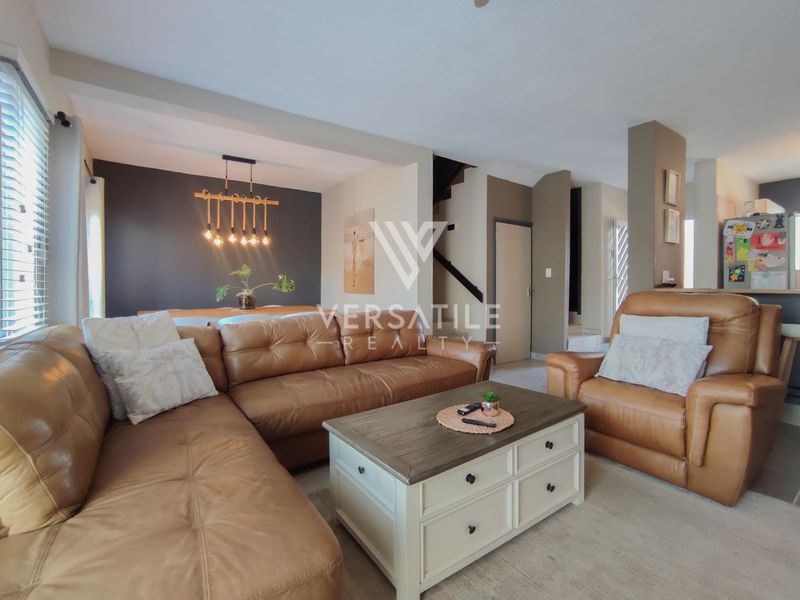 Open plan living and dining area featuring neutral wall tones, a staircase, and modern pendant lighting.