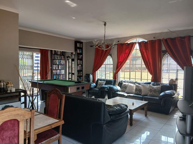 Spacious living area featuring large arched windows, tiled flooring, and built-in shelving, offering a comfortable space for relaxation and entertainment.