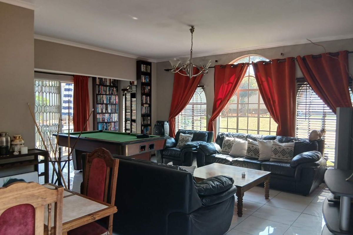 Spacious living area featuring large arched windows, tiled flooring, and built-in shelving, offering a comfortable space for relaxation and entertainment.