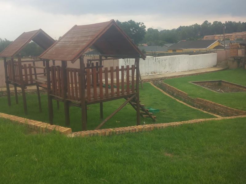 A large garden area featuring a sunken pool shell, brick edging, and wooden play structures, requiring landscaping and maintenance.