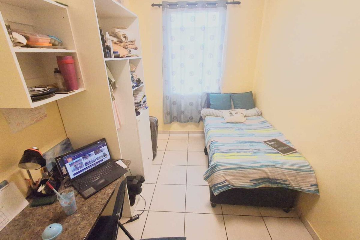 A compact bedroom featuring tiled flooring and built-in shelving units, providing functional storage space.