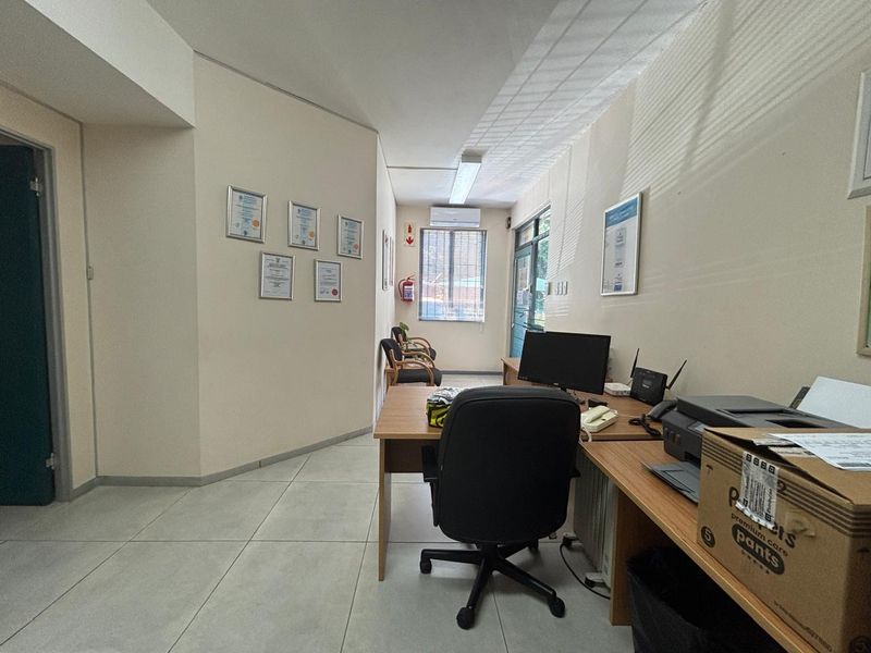A functional office space featuring tiled flooring, air conditioning, and natural light through window blinds, suitable for professional use.
