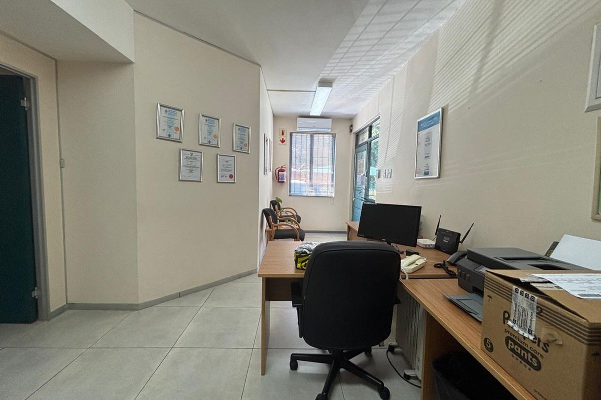 A functional office space featuring tiled flooring, air conditioning, and natural light through window blinds, suitable for professional use.