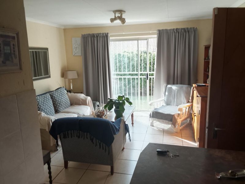 A functional living room featuring tiled flooring and a sliding glass door with a security gate, providing direct access to the outdoor area.