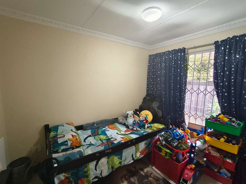 A standard bedroom featuring a security gate on the window and decorative ceiling cornicing.
