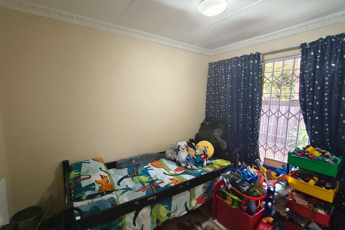 A standard bedroom featuring a security gate on the window and decorative ceiling cornicing.