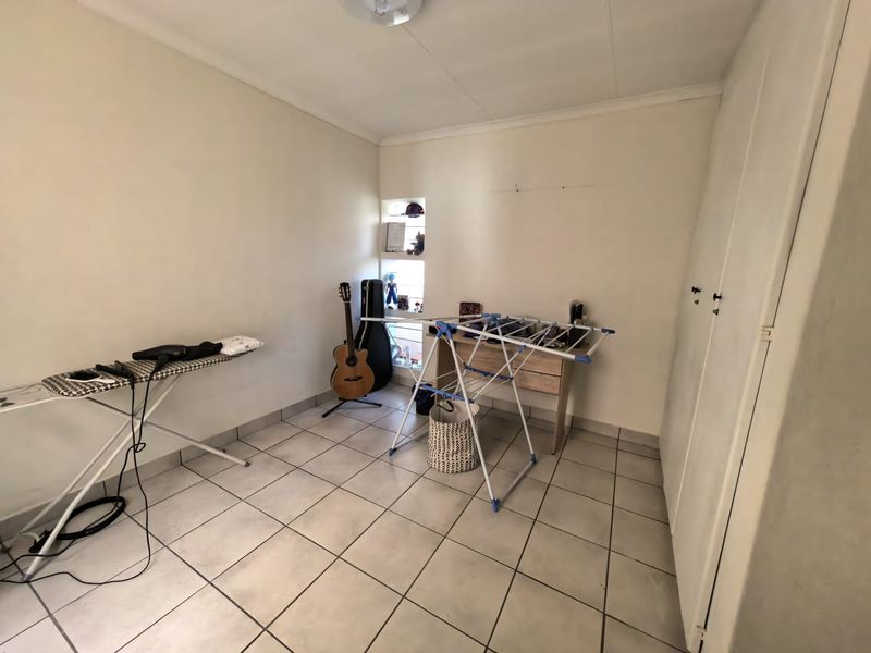 A functional bedroom featuring tiled flooring, built-in cupboards, and a small recessed wall shelving unit.
