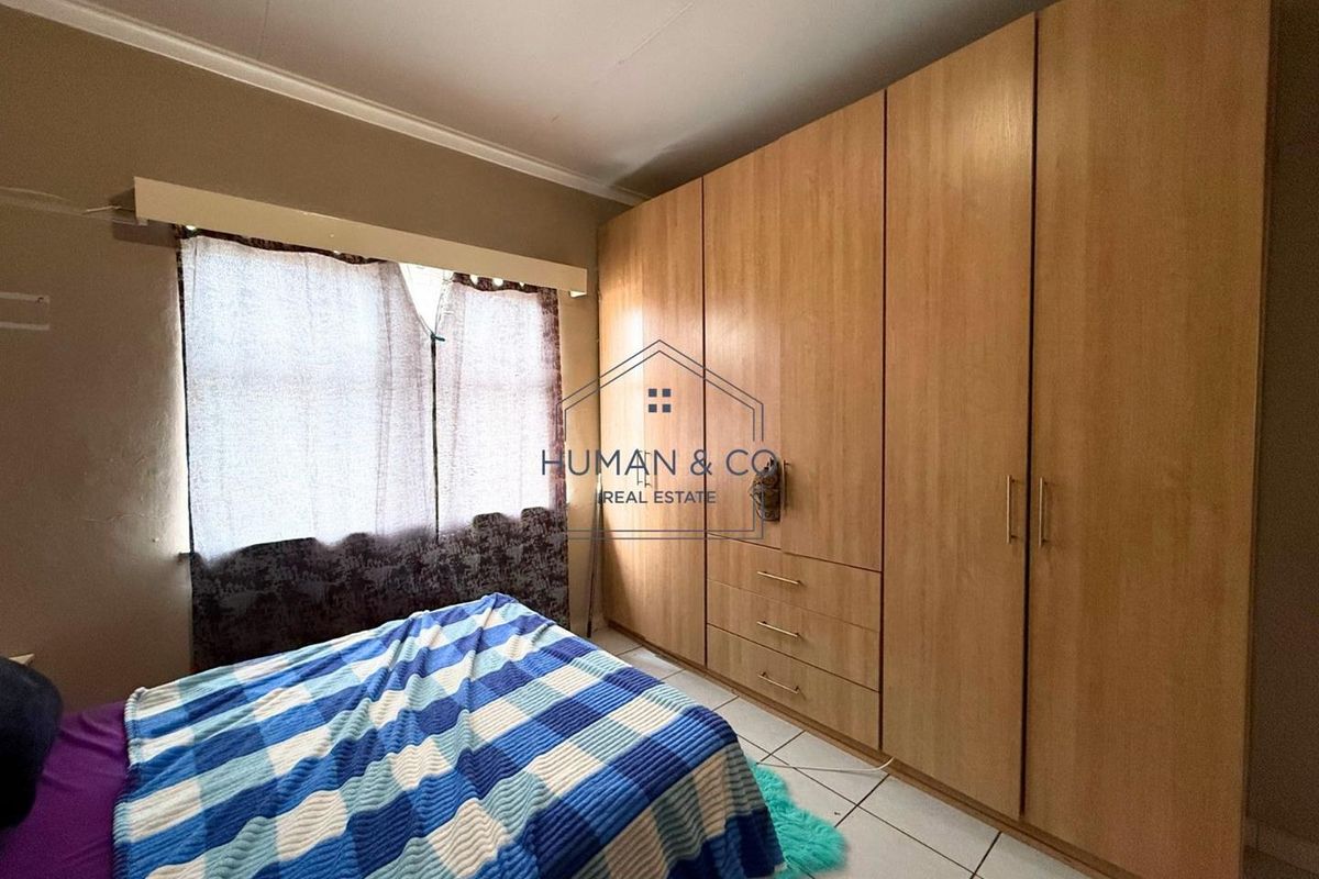A bedroom featuring built-in wooden cupboards and tiled flooring, providing functional storage space.