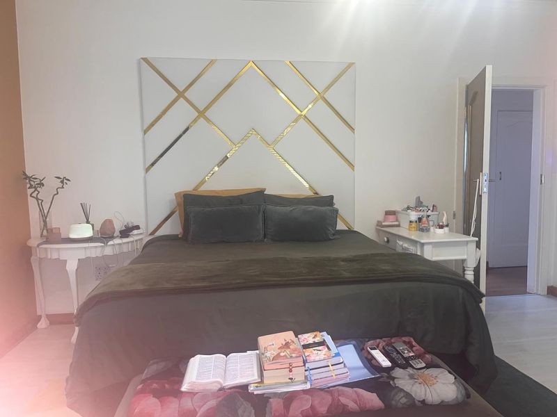 A well-maintained bedroom featuring a modern geometric gold-accented decorative wall panel behind the bed area.