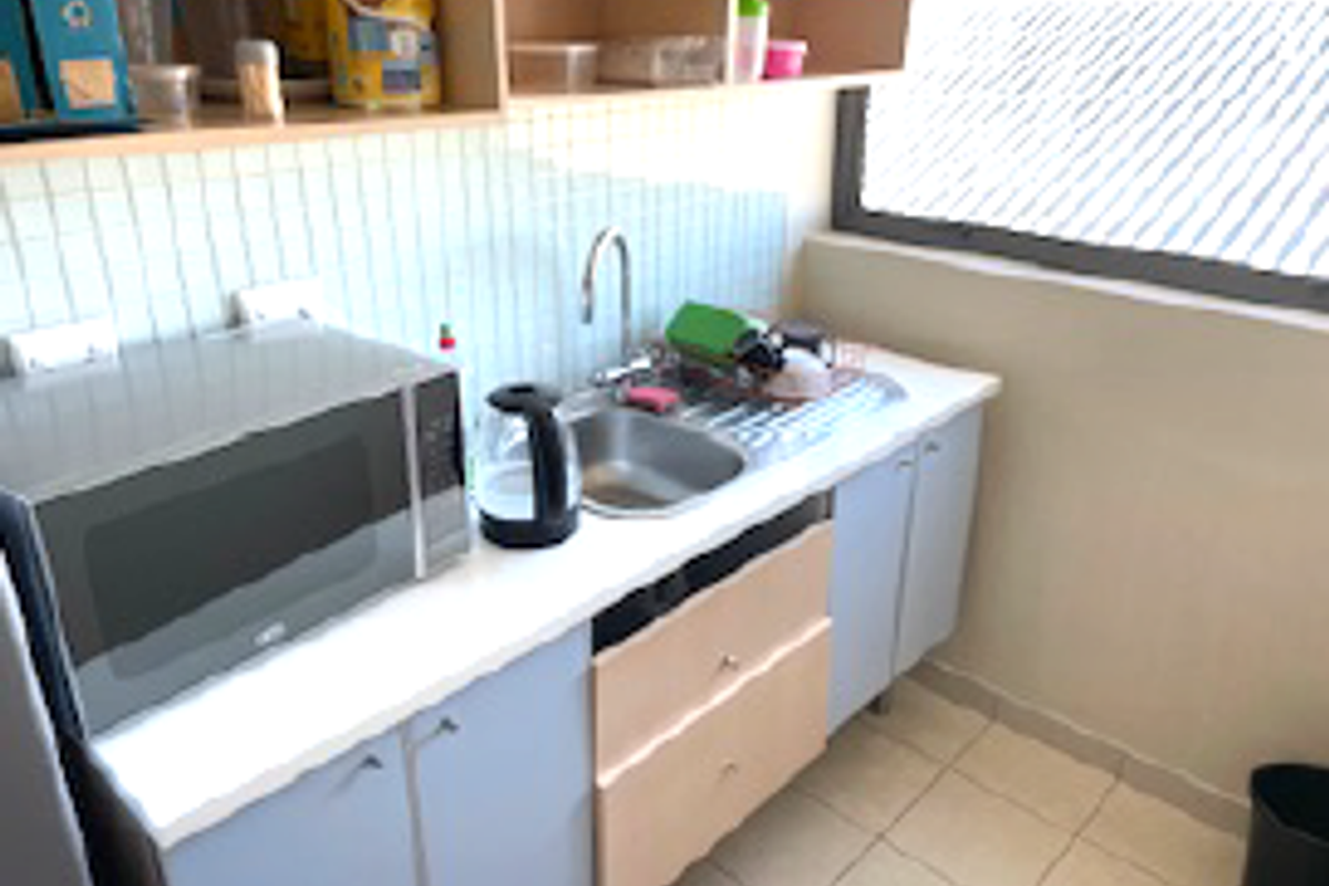 Compact kitchenette featuring a stainless steel sink, tiled backsplash, and built-in cabinetry with overhead storage shelves.