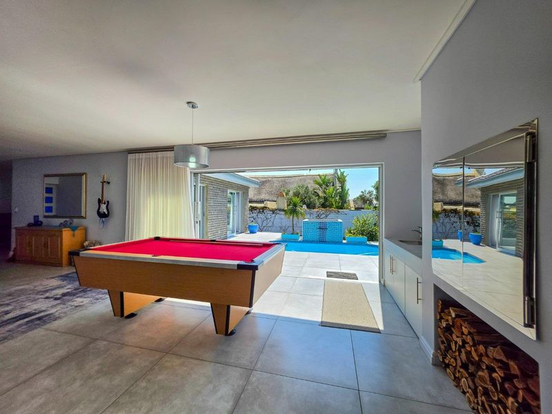 Spacious living area featuring tiled floors, built-in cabinetry with a sink, and large sliding doors opening directly to the pool area.