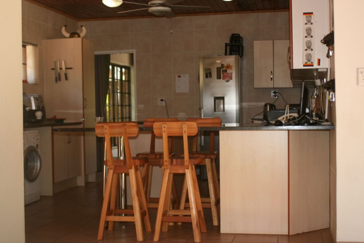 A functional kitchen featuring a breakfast bar, tiled walls, and built-in cabinetry with integrated appliance space.