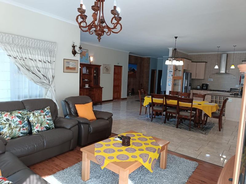 Spacious open-plan living and dining area featuring a functional kitchen with built-in cabinetry and a mix of tiled and wooden flooring.