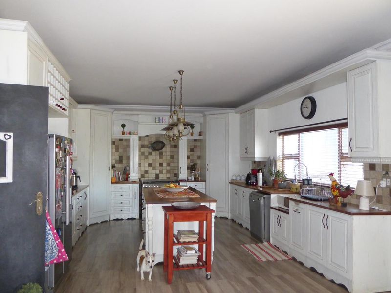 Spacious kitchen featuring white cabinetry, wooden countertops, a central island, and a tiled backsplash, offering a classic and functional cooking environment.