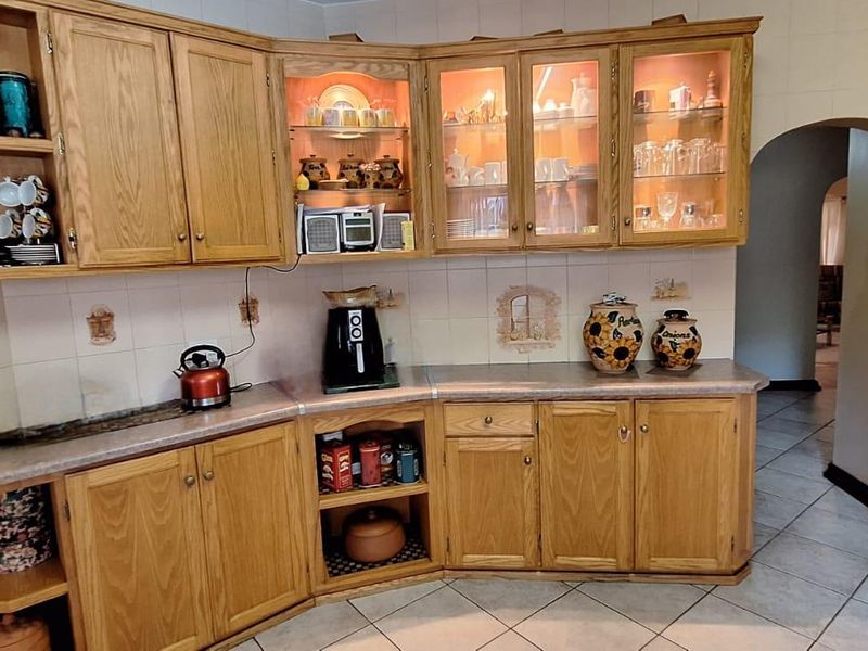 A traditional kitchen featuring oak cabinetry, laminate countertops, tiled backsplash, and glass-front display cabinets with integrated lighting.