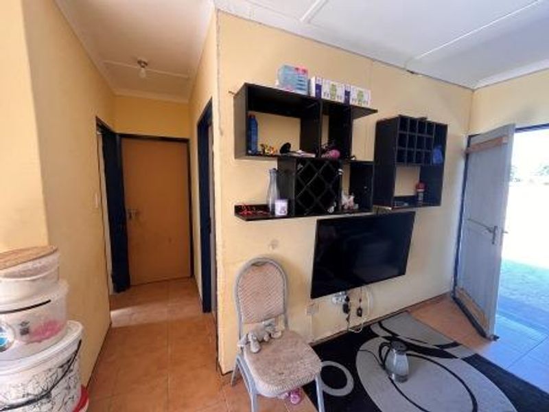 A living area featuring tiled flooring and built-in wall shelving, requiring cosmetic updates to improve the overall aesthetic and condition.