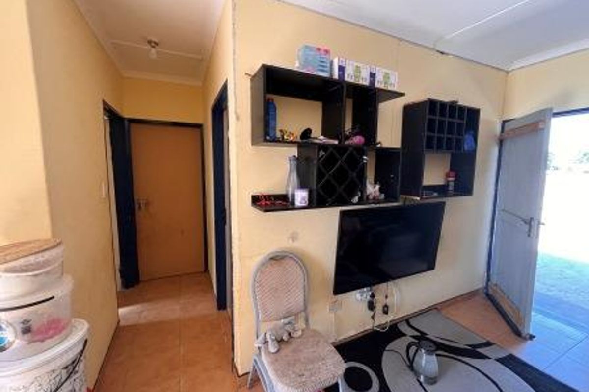 A living area featuring tiled flooring and built-in wall shelving, requiring cosmetic updates to improve the overall aesthetic and condition.