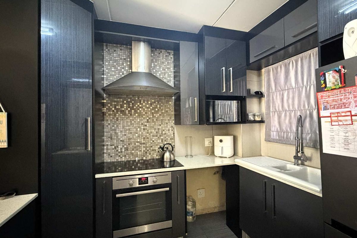 Modern kitchen featuring dark cabinetry, mosaic tile backsplash, stainless steel appliances, and stone countertops, with an efficient layout for cooking and preparation.