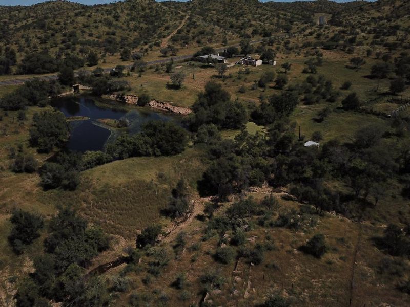 An aerial view of a rural property featuring natural landscape, vegetation, and a water body.